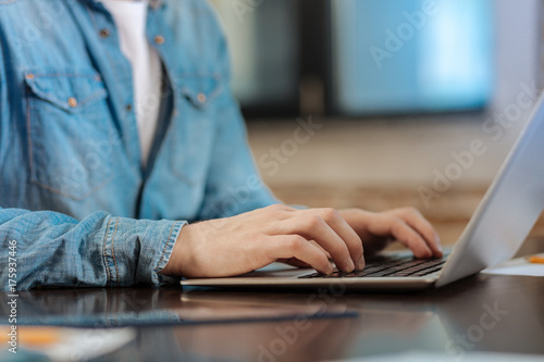 Close up of man in denim shirt typing on laptop