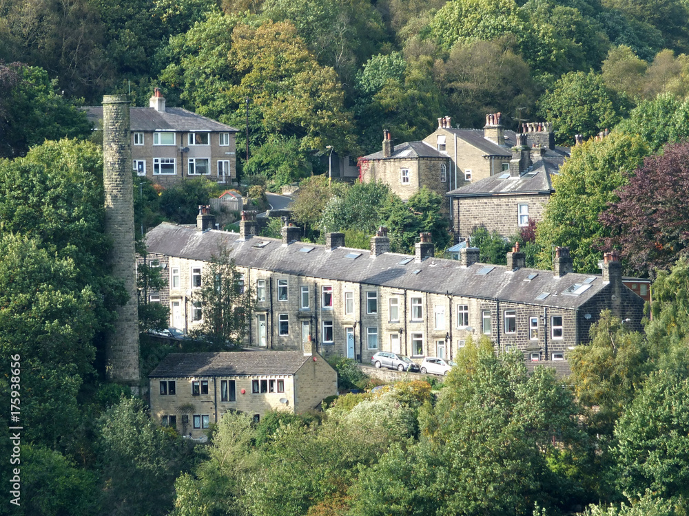 terraced houses amongst the trees on steep hills with old mill chimney in Hebden Bridge west yorkshire