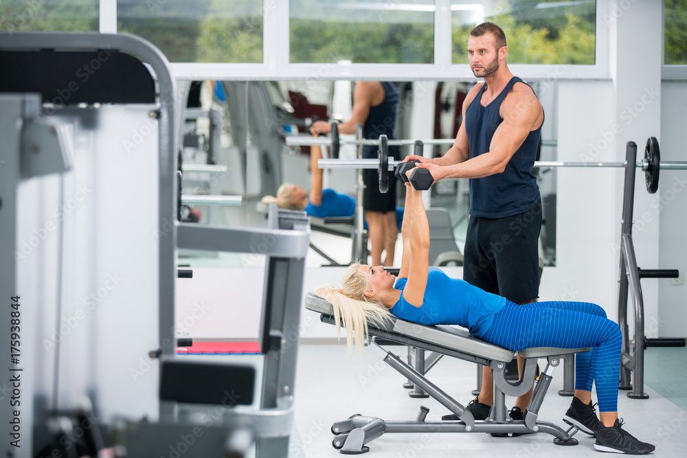 Young couple working out with dumbbells at gym Young couple working out with dumbbells at gym