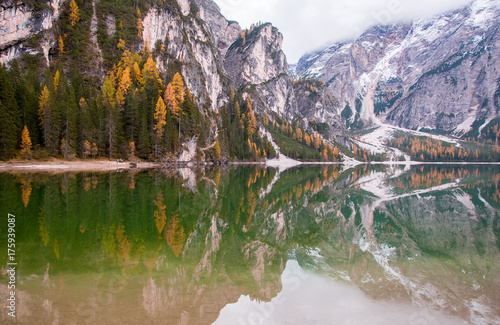 Mountain rocks and autumn forest reflected in water of Braies Lake, Dolomite Alps, Italy