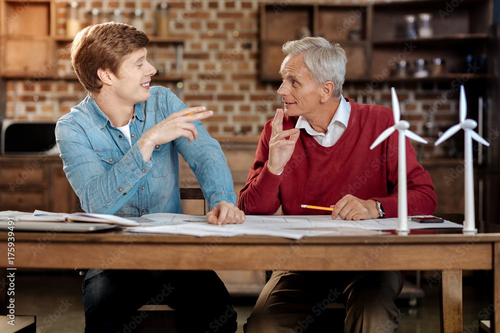 Upbeat young man sharing ideas with his senior colleague Upbeat young man sharing ideas with his senior colleague