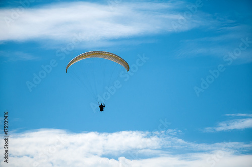 Paraglider flying in the blue sky against the background of clouds. Paragliding in the sky on a sunny day.