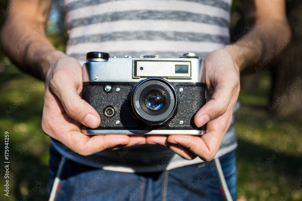 Obraz premium Young man holding in hands old vintage camera. Man photographer and film retro camera. Say cheese!