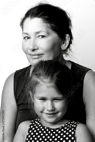  Affectionate grandmother and her cute little granddaughter smile at the camera