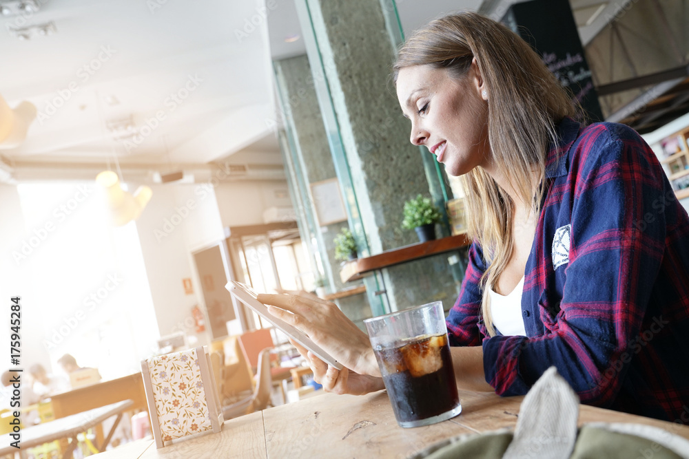 Cheerful woman in coffee shop using digital tablet Cheerful woman in coffee shop using digital tablet