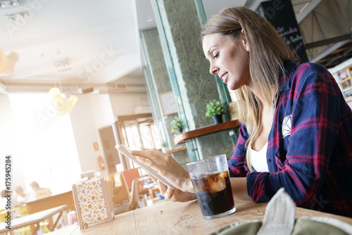 Cheerful woman in coffee shop using digital tablet