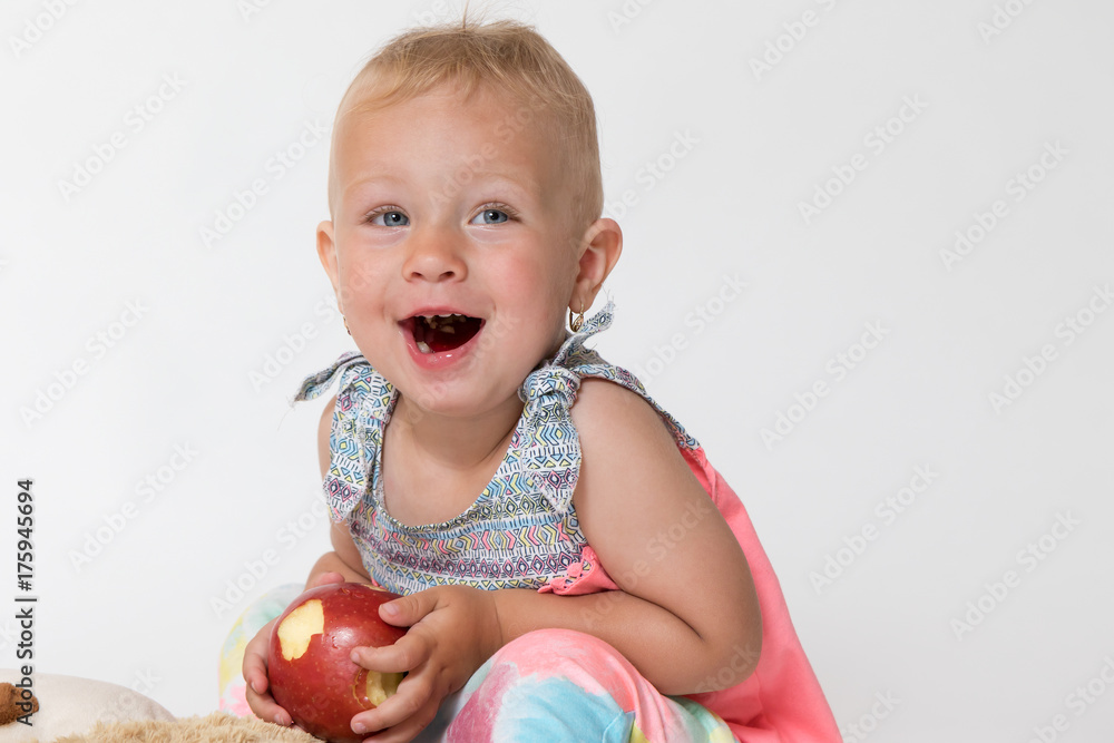 Laughing toddler girl is holding red apple Laughing toddler girl is holding red apple