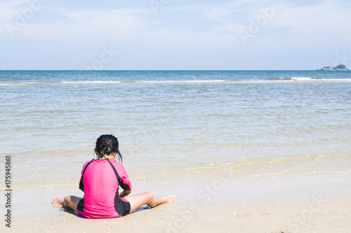 Girl child sitting and playing with sand on beach outdoor childhood and happiness summer vacation in Thailand beach.