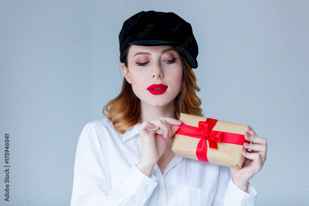 Young redhead woman in hat holding christmas gift box Young redhead woman in hat holding christmas gift box