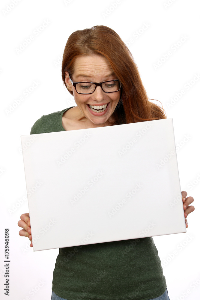 Hübsche rothaarige Frau mit Brille schaut auf eine weisse Tafel Hübsche rothaarige Frau mit Brille schaut auf eine weisse Tafel