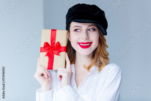 Young redhead woman in hat holding christmas gift box