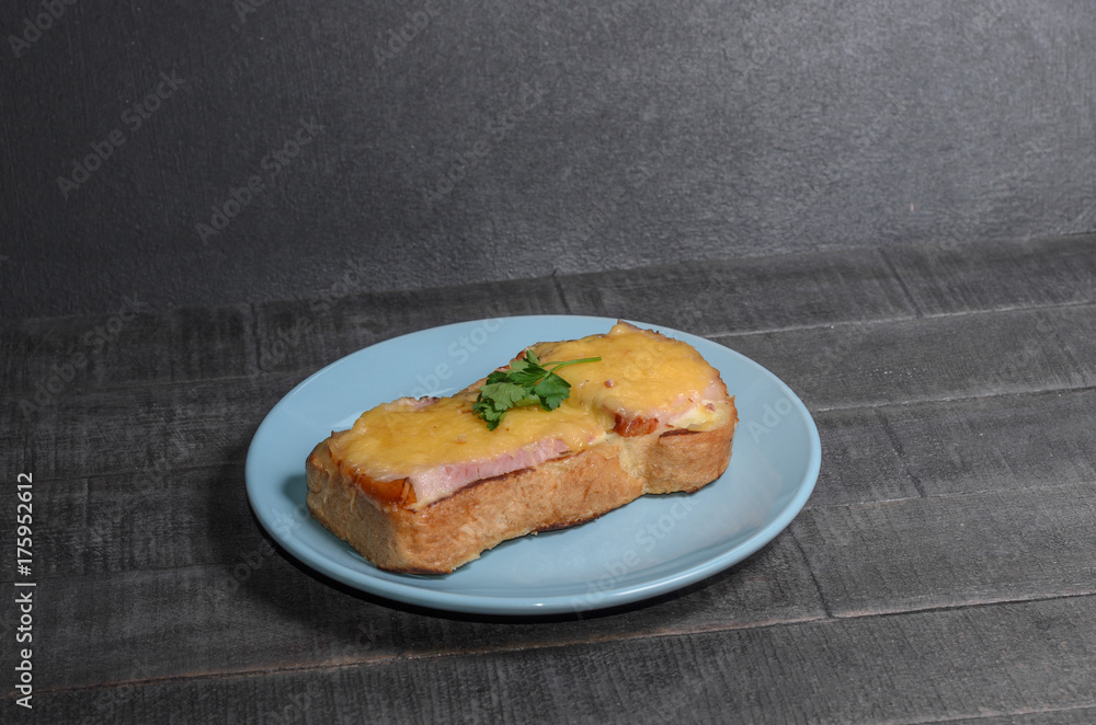 Sandwich with meat, cheese and greens on a blue plate Sandwich with meat, cheese and greens on a blue plate