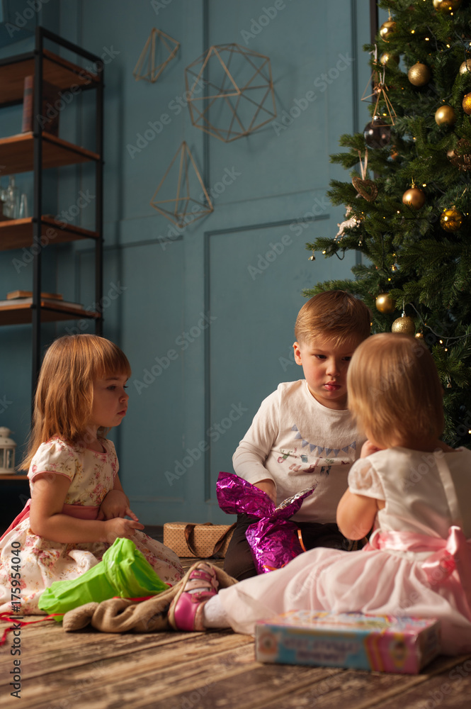 Excited children with gifts next Christmas tree