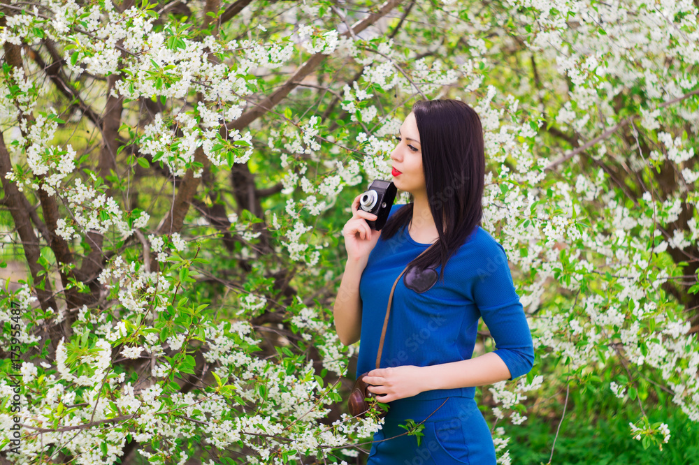 A young woman with retro camera photographing a blue dress A young woman with retro camera photographing a blue dress