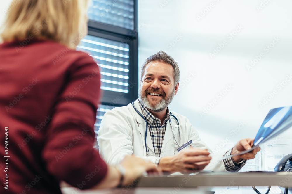 Fototapeta premium Happy doctor talking with patient in his office