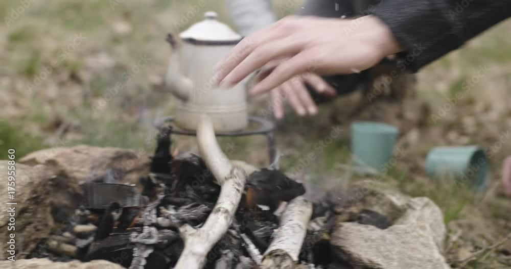 Man punting wood logs on fire place near camping tent place. while woman preparing hot beverage. Couple people in love autumn outdoor trip in nature. Fall sunny day. 4k slow motion video Man punting wood logs on fire place near camping tent place. while woman preparing hot beverage. Couple people in love autumn outdoor trip in nature. Fall sunny day. 4k slow motion video