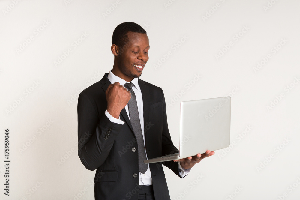Black male smiling manager in suit standing, holding laptop at hands. Portrait Black male smiling manager in suit standing, holding laptop at hands. Portrait