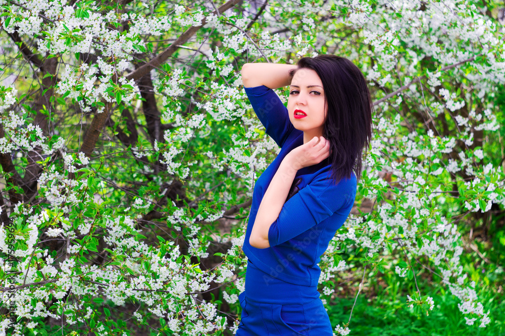 Young beautiful woman in spring blossoming garden