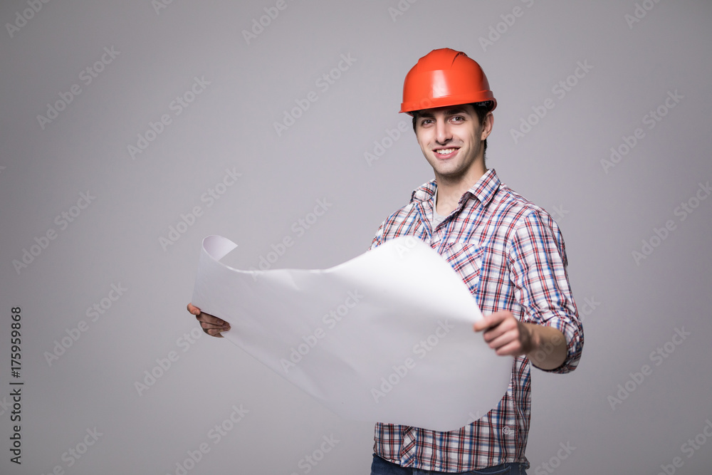 Handsome Man in a black suit and construction helmet looking to the side and holding black folder on grey Handsome Man in a black suit and construction helmet looking to the side and holding black folder on grey