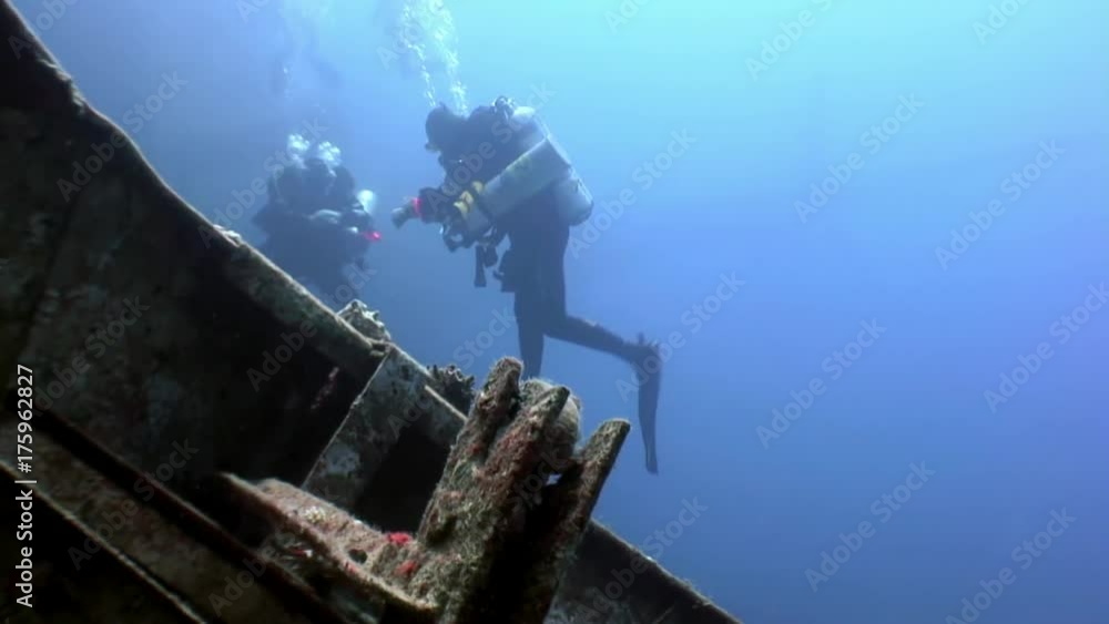 Scuba divers swimming explore shipwreck Salem Express deep underwater Red sea. Secret of sunken ship which crashed on coral reef. Historical place of tragedy. Scuba divers swimming explore shipwreck Salem Express deep underwater Red sea. Secret of sunken ship which crashed on coral reef. Historical place of tragedy.