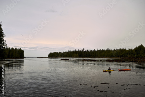 Person kayaking in a tranquil bay at sunrise