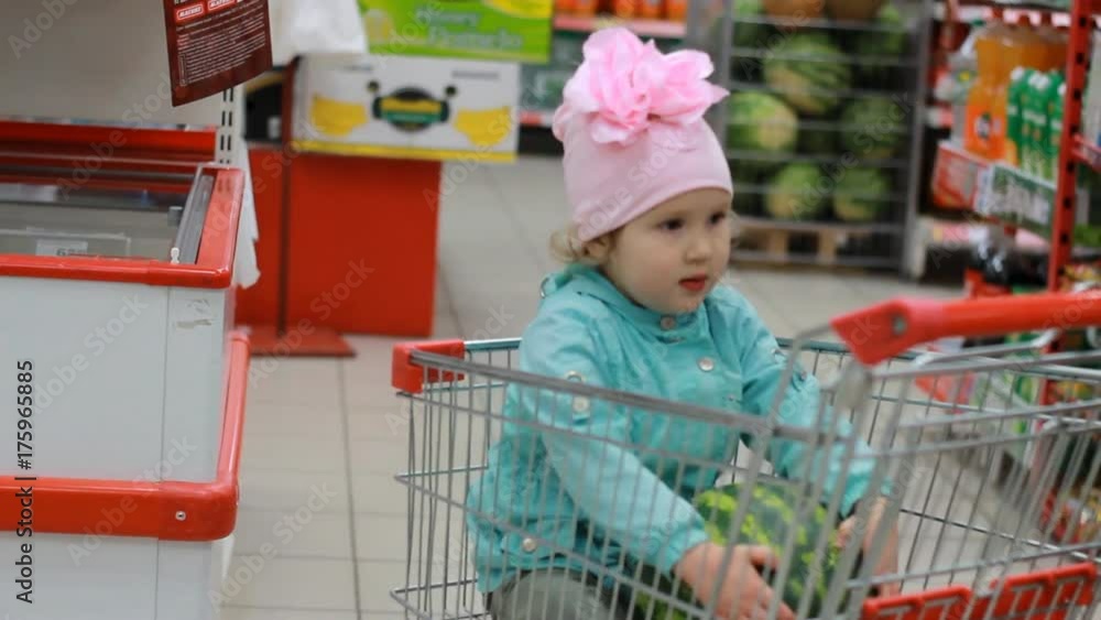 Disgruntled little girl in the supermarket is sitting in a cart for food. The child is upset and crying Disgruntled little girl in the supermarket is sitting in a cart for food. The child is upset and crying
