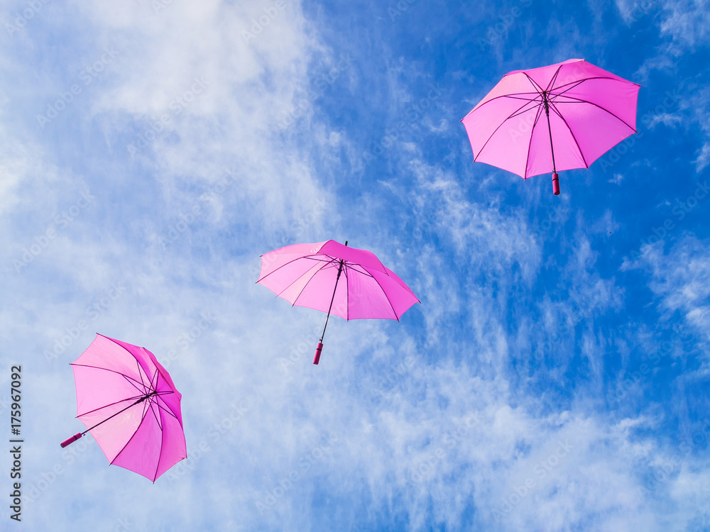 Regenschirme in pink fliegen vor blauem Himmel diagonal - Umbrellas in pink fly before blue sky diagonal