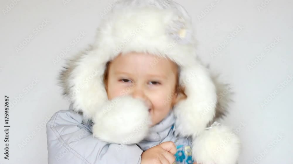 A funny happy child dressed in warm fur clothes looks at the camera, laughs and smiles. Close-up portrait. The concept of winter, frost and snow, cold weather, Cool temperature and Christmas A funny happy child dressed in warm fur clothes looks at the camera, laughs and smiles. Close-up portrait. The concept of winter, frost and snow, cold weather, Cool temperature and Christmas