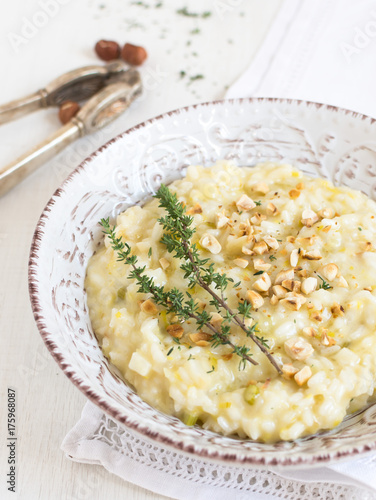 Risotto with green celery, turnip celery and taleggio cheese, decorated with thyme, roasted hazelnuts and acacia honey. Italian recipe for Mediterranean cuisine. Close-up view.
