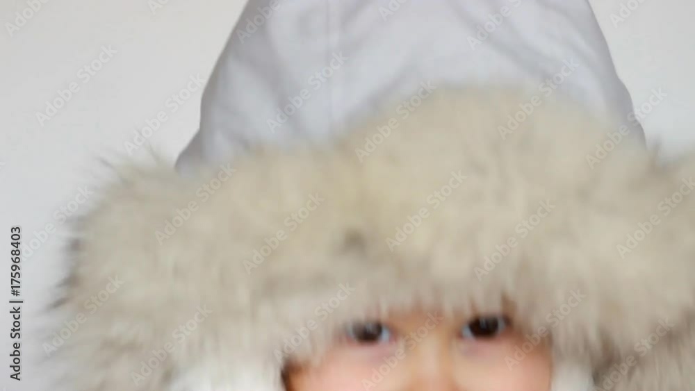 A funny happy child dressed in warm fur clothes looks at the camera, laughs and smiles. Close-up portrait. The concept of winter, frost and snow, cold weather, Cool temperature and Christmas. A funny happy child dressed in warm fur clothes looks at the camera, laughs and smiles. Close-up portrait. The concept of winter, frost and snow, cold weather, Cool temperature and Christmas.