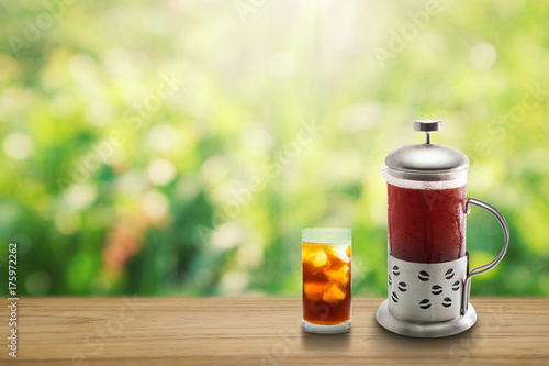Coffee clod brew process (Method). Full glass of cold black coffee on teak wooden table. Isolated on green yellow nature light bokeh background with clipping path.