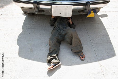 Child under a car fixing an engine photo