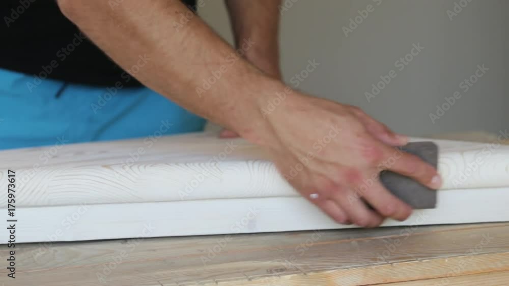 Close-up of male hands polishing wooden step with sandpaper Close-up of male hands polishing wooden step with sandpaper