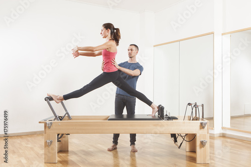 Pilates lesson on reformer, personal coaching young beautiful woman