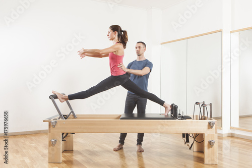 Pilates lesson on reformer, personal coaching young beautiful woman