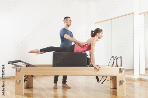 Pilates lesson on reformer, personal coaching young beautiful woman