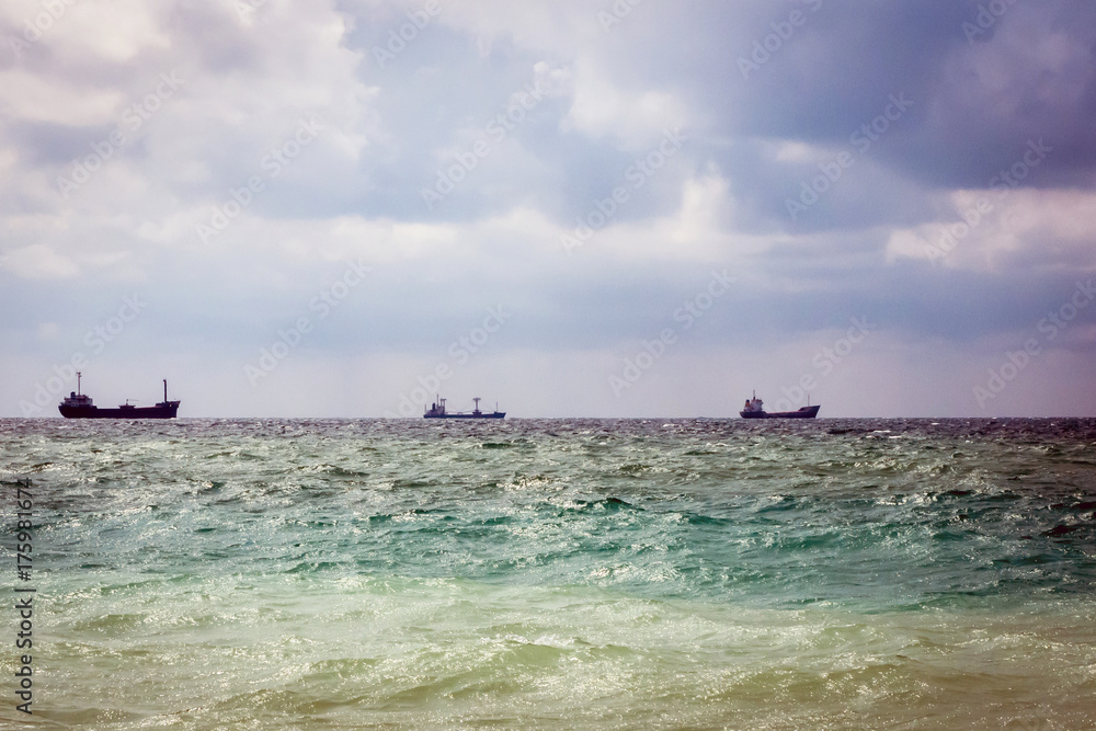 three cargo ship on the horizon in the sea. cloudy sky