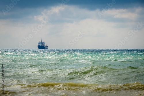 cargo ship on the horizon in the sea. cloudy sky © Roman