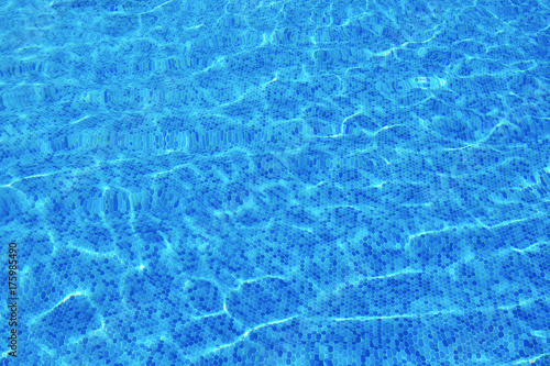 Small elements blue mosaic on the bottom of the pool pattern. Wavy water surface. Travel background.