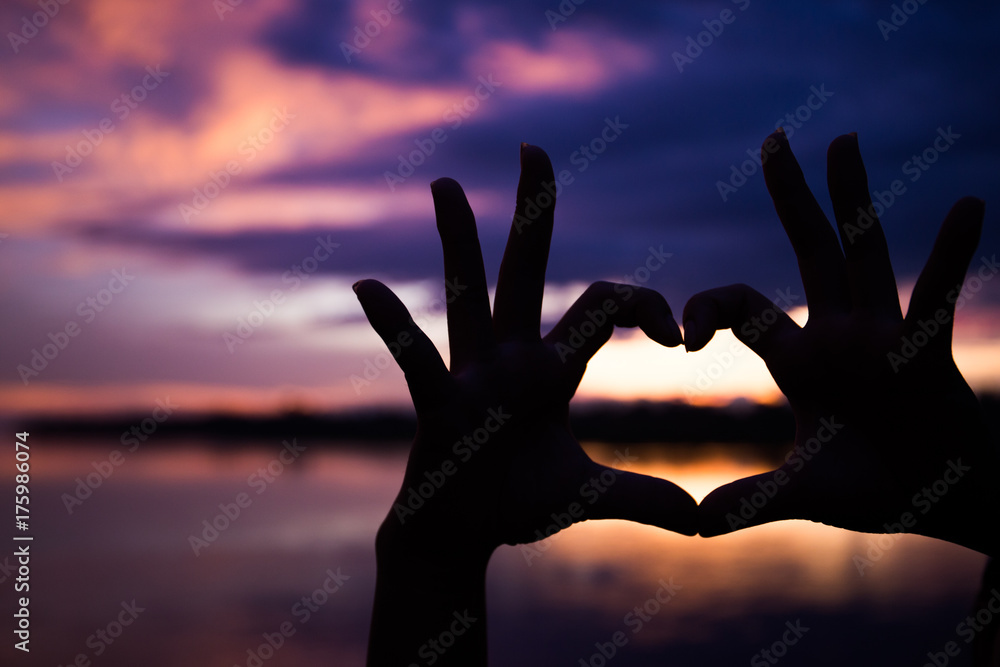 Silhouette of hands with heart shape with beautiful color sunset background Silhouette of hands with heart shape with beautiful color sunset background