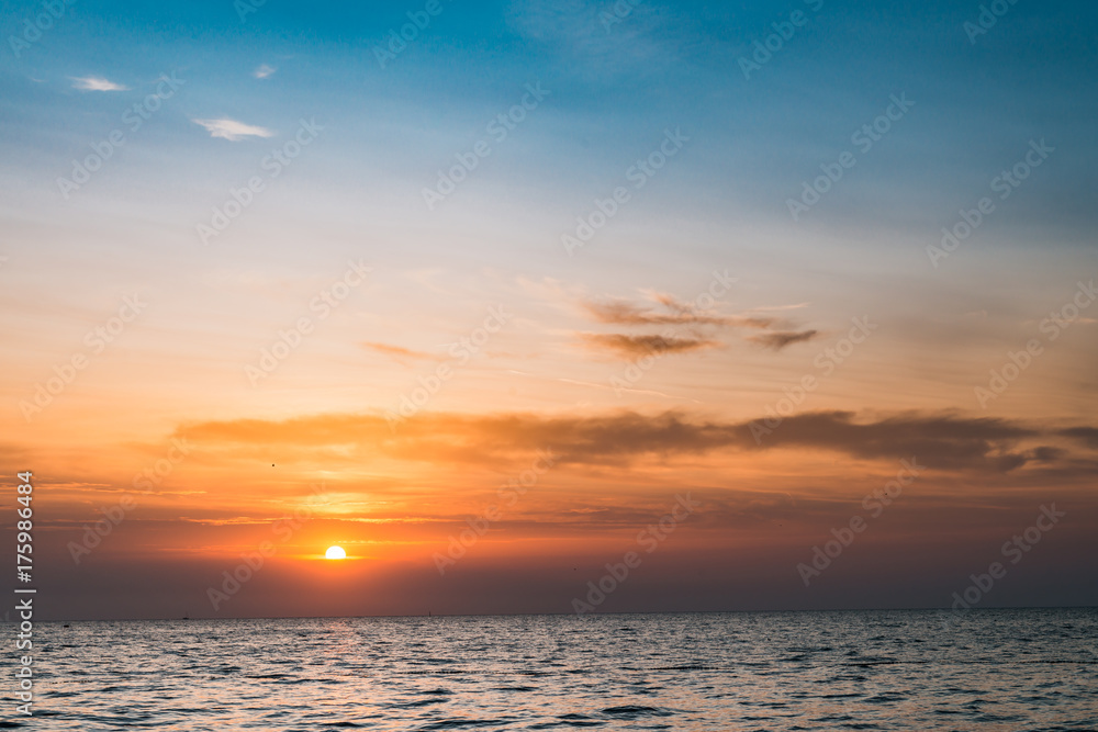 Cloudy layered sunset on the ocean. Background for peacefulness