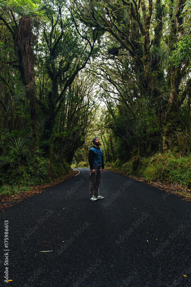 Man standing alone on secluded road in rain forest Man standing alone on secluded road in rain forest
