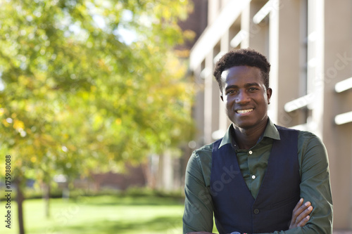 Handsome young black student man smiles standing on colege campus