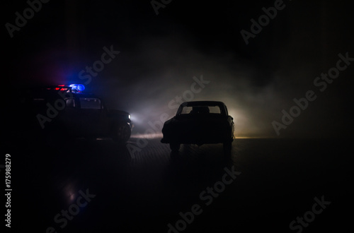 Police car chasing a car at night with fog background. 911 Emergency response police car speeding to scene of crime