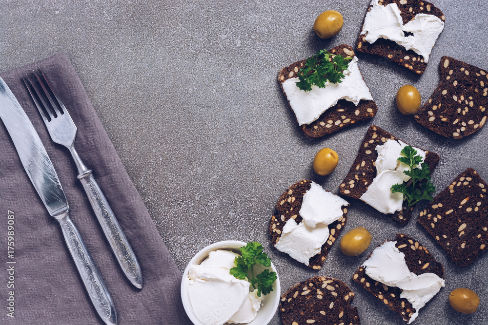 Rye crackers with cheese on a gray surface. An old fork and knife nasalfetke.
