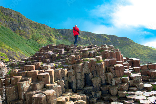 A man in a Landscape of Giant's Causeway trail with a blue sky in summer, Co. Antrim, tourism in Northern Ireland in United Kingdom. UNESCO heritage. photo