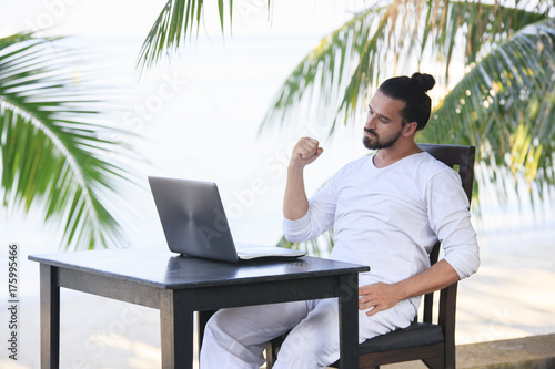 Man relaxing on the beach with laptop, freelancer show win © yuliyatrukhan