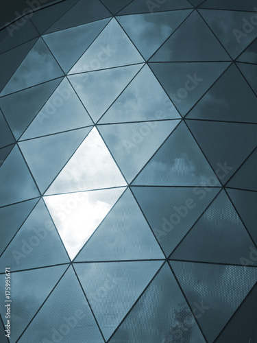 modern glass triangualr cladding windows with sky and clouds reflected