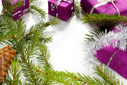 Small Christmas tree decorated with toys stands on the table with red cones on a bright purple background for an inscription.