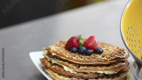 stack of waffles with berries on top and in a yellow bowl
